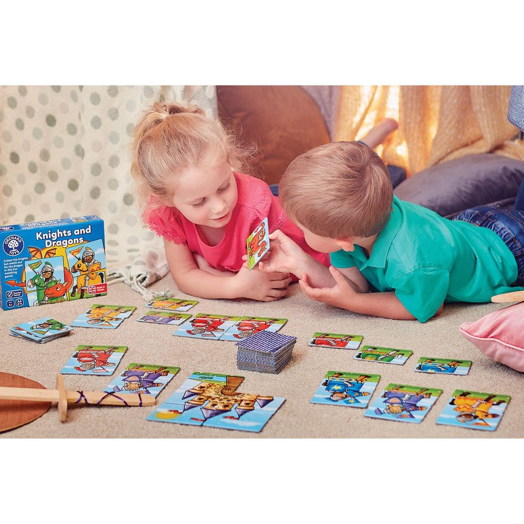 Two children playing with a 'Knights and Dragons' card game on a carpeted floor.